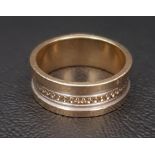 TWO TONE FOURTEEN CARAT WHITE AND YELLOW GOLD RING with circular engraved detail around the centre