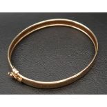 NINE CARAT GOLD BANGLE with safety clasp, approximately 6.3 grams