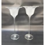 PAIR OF LARGE GLASS CANDLE HOLDERS raised on a circular foot with a narrow stem and flower head