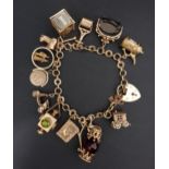 GOOD NINE CARAT CHARM BRACELET with heart padlock clasp and an interesting selection of gold charms,