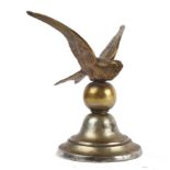 An early 20th century brass car mascot in the form of a swift, its wings upswept, on moulded domed