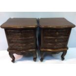 A pair of reproduction stained and carved mahogany three drawer bedside tables, raised on cabriole