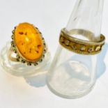 A 9ct yellow gold oval cabochon shaped amber dress ring with filigreed edging, finger size O,