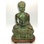 A patinated bronze Bodhisattva/ Buddha, seated in meditation and holding a pine cone, raised on