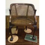 An early 20th century walnut Bergere style caned armchair raised on carved legs to claw and ball