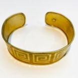 A 9ct yellow gold open bangle with greek key design to the outside, weighing 16.6 grams, width 20mm.