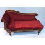 A Victorian mahogany short chaise lounge, with deep red fabric upholstery and cylindrical cushion,