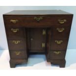 A George III stained oak kneehole desk, with single long frieze drawer, above a central cupboard,