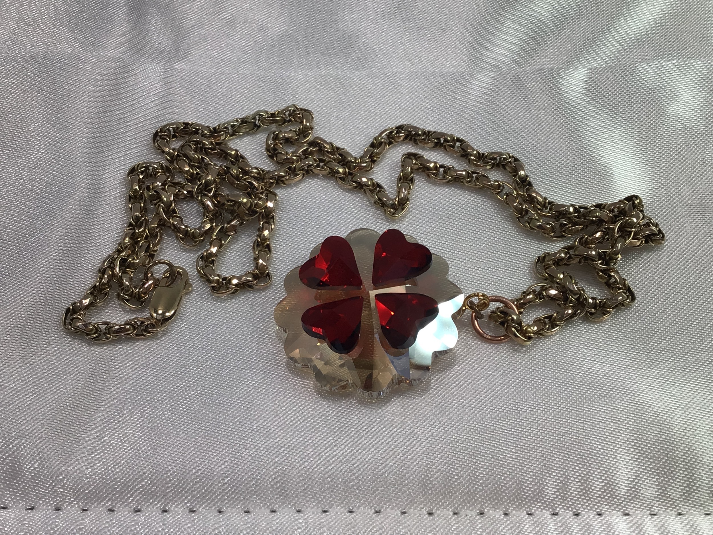 A 9ct gold belcher link chain with glass pendant with four red hearts formed as a stylised four leaf