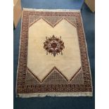 A traditional hand made geometric oriental wool rug with a central crest on a cream background and
