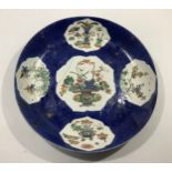 A Chinese 'powder blue' ground dish with lotus reserves painted in famille verte enamels with
