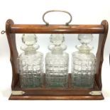 An oak and metal bound three section tantalus, with three glass decanters and stoppers, 35cm