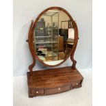 An oval mahogany bow platform mirror, with three frieze drawers and raised on shaped bracket feet,