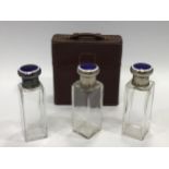 An early 20th century travelling set of three cut glass perfume bottles of rectangular form, white
