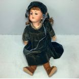 A German bisque headed doll with brown hair, sleeping bright blue eyes, mouth parted, jointed