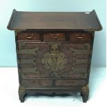 A 20th century stained hardwood alter table cabinet with scrolled top, three frieze drawers above