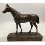 A bronze figure of a standing horse looking left with painted blaze and fetlocks, raised on