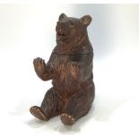 A Black Forest carved wooden inkwell modelled as a seated brown bear, with hinged head enclosing