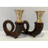 A pair of cast and patinated bronzed candlesticks modelled as rams horns with silvered sconces, 18cm