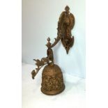 A large wall hanging brass bell, with decorative pierced and scrolled bracket and support, the