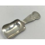 A silver caddy spoon of shovel form with foliate engraved finial, Birmingham, 1945, maker's initials