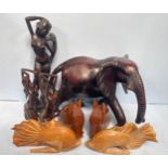An African hardwood figure of an elephant, 50cm long, together with three carved wooden female