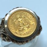 A 9ct gold ring, set with a gold Mexican coin to the top, ring has heavily carved shoulders and