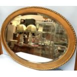 A large heavy oval gold painted mirror with bevelled glass and ornate frame, 110cm wide