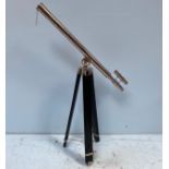 A modern chrome telescope, raised on a black painted, wooden and chrome adjustable tripod base,