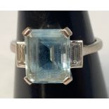An 18ct white gold ring set with an emerald cut aquamarine to the centre, flanked by a baguette