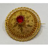 An imported 18ct gold circular filigree brooch, set to the centre with a round faceted ruby, 4.4g,