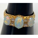 An 18ct yellow gold dress ring set with three oval shaped fiery opals, with four small diamonds in-