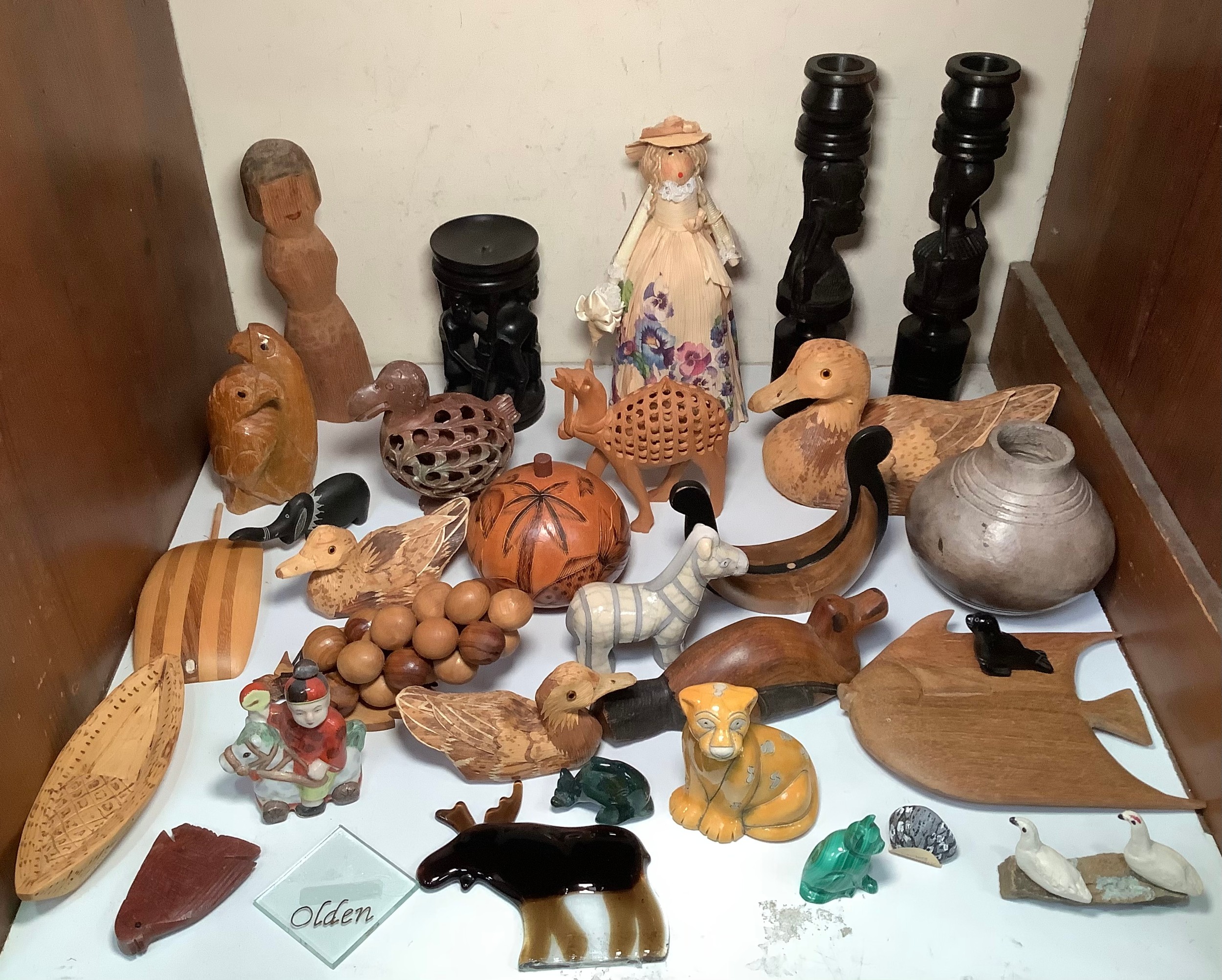 A collection of various wood and soapstone carvings including African candle sticks, ducks, grapes