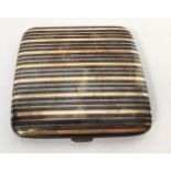 An Art Deco Silver, Niello work and gold inlaid pocket cigarette case, with black and gold striped