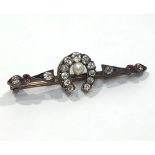 A diamond horseshoe bar brooch set with eleven diamonds and central pearl, further set to the