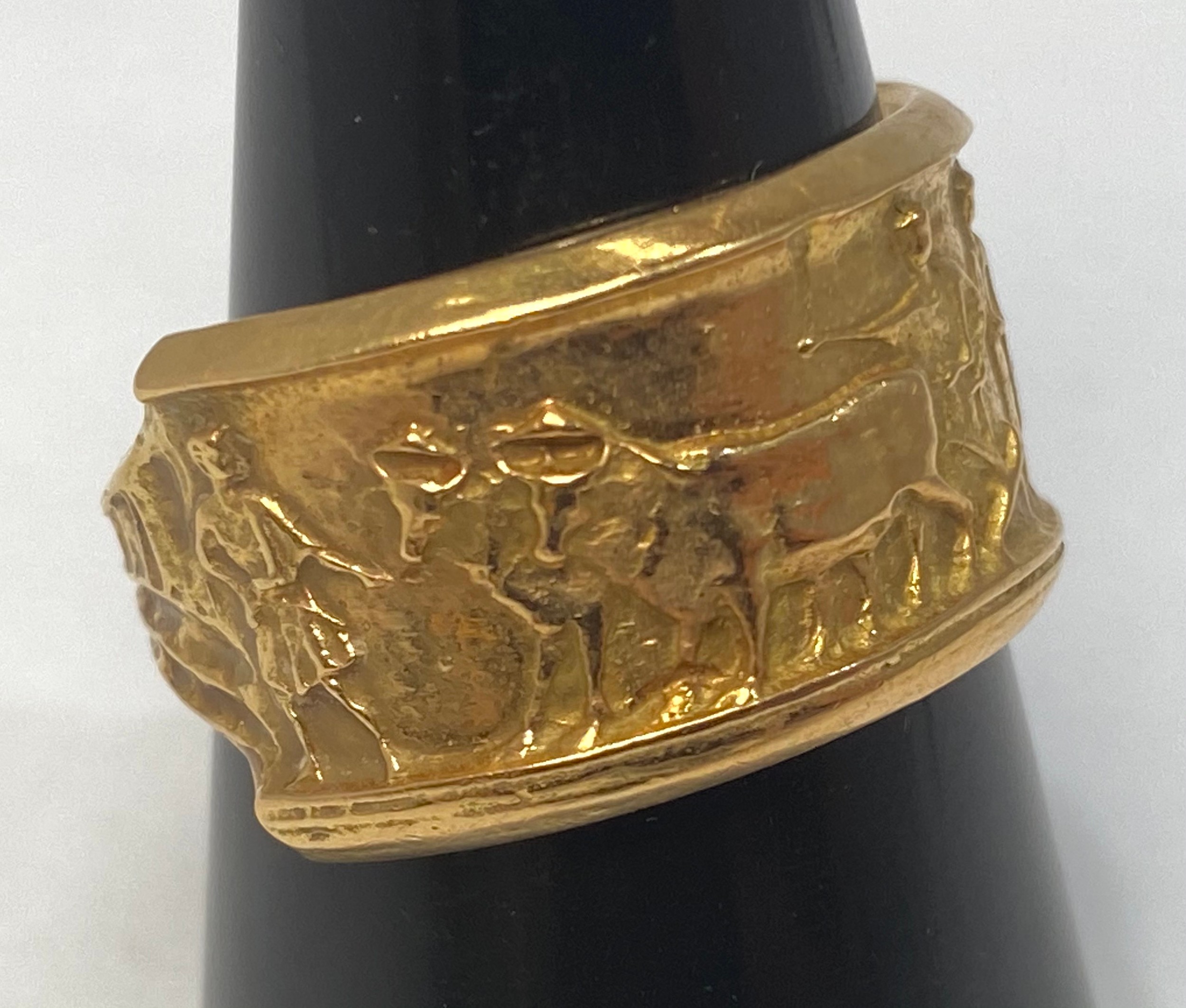 An 18ct gold ring, cast with bulls and robed figures, weighs 7.9 grams, finger size S.