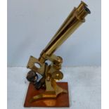 A 19th century brass binocular microscope by Edmund Wheeler of London, mounted on wooden base,