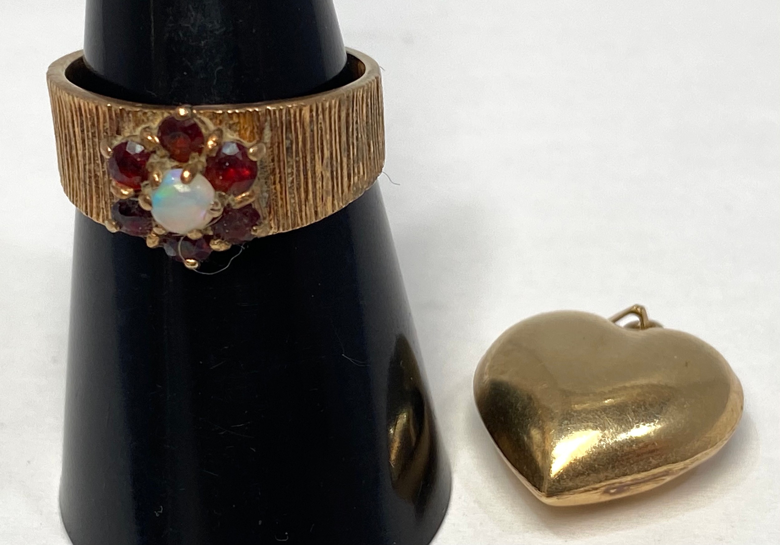 A 9ct gold ring with textured shank, set with an opal to the centre with garnets surrounding, ring