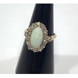 A diamond and opal ring, tests as 18ct gold, central cabochon opal surrounded by fifteen small