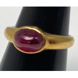 An 18ct gold ruby ring, set with an oval cabochon cut ruby in a rub-over setting, ring weighs 4.6