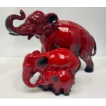 A Royal Doulton flambe elephant with trunk raised, 16cm high, together with a flambe elephant & calf