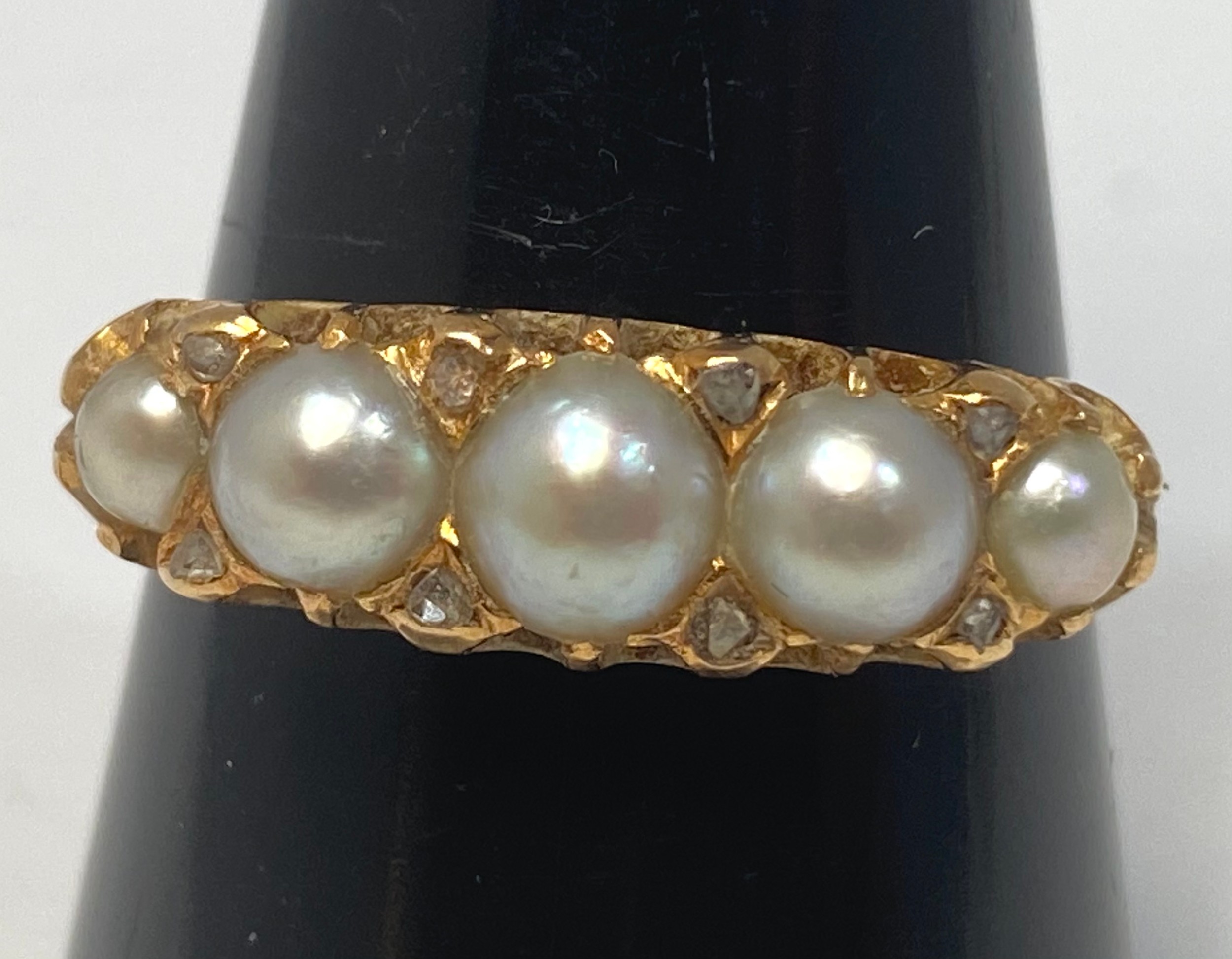 A 9ct gold ring set with five graduated blister-pearls, and 8 x small eight-cut diamonds in a carved