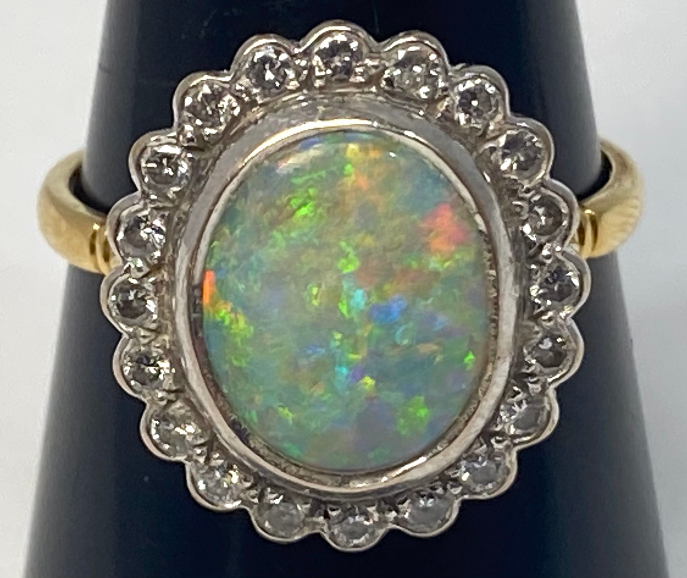 An 18ct gold opal and diamond ring, set with an oval fiery opal, measuring approximately 14mm x