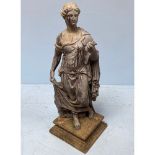 A cast metal statue of a Roman woman, in typical dress and holding sticks in one hand, raised on