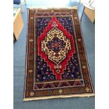 A large hand-knotted Turkish rug with a cream, red and blue central medallion to a red ground with