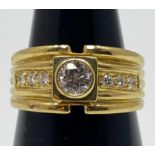 An 18ct yellow gold wide band dress ring, set with a round brilliant cut diamond to the centre,