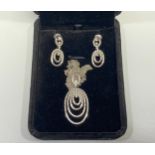 An 18ct white gold necklace and earring suite, comprising a double chain with graduated oval pendant
