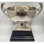 A large silver trophy bowl by Mappin & Webb, with twin scrolled, floral handles and raised on square