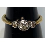An 18ct yellow gold diamond ring, set with three round brilliant cut diamonds in a rub-over bezel