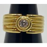 An 18ct yellow gold wide band dress ring, set with a round brilliant cut diamond to the centre, in a